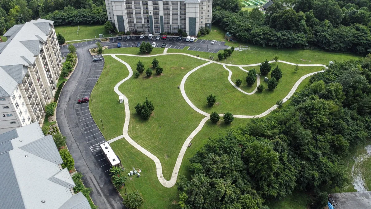 A tranquil exterior shot showcases manicured lawns, winding walking paths, and surrounding trees, set against the backdrop of a relaxed, open atmosphere. The expansive green space is ideal for walks, games, and outdoor gatherings, inviting families to explore and unwind together.