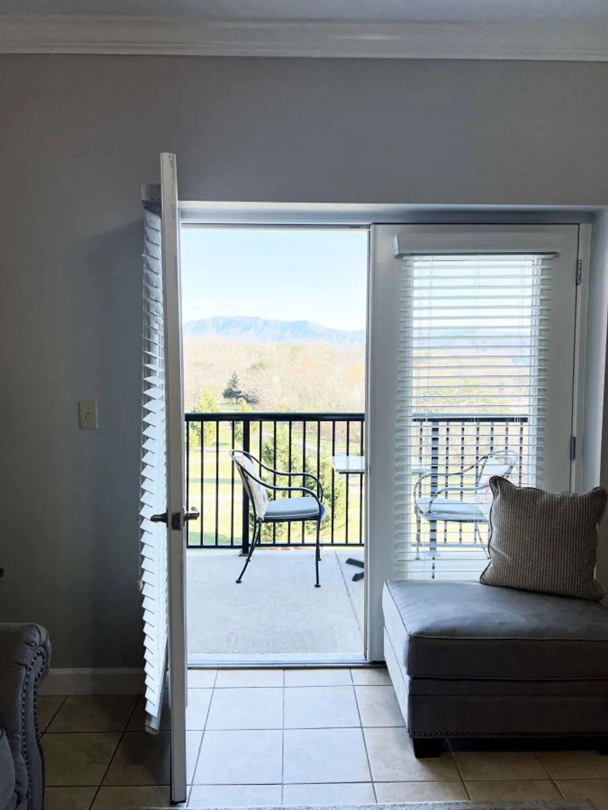 The image showcases an inviting interior with an open door leading to a private balcony. From this perch, guests can enjoy a stunning, unobstructed view of the Smoky Mountains. The outdoor seating area hints at relaxing moments, like sipping coffee at sunrise or unwinding with loved ones as the day fades into evening. The overall mood is peaceful and welcoming, promising a serene escape.
