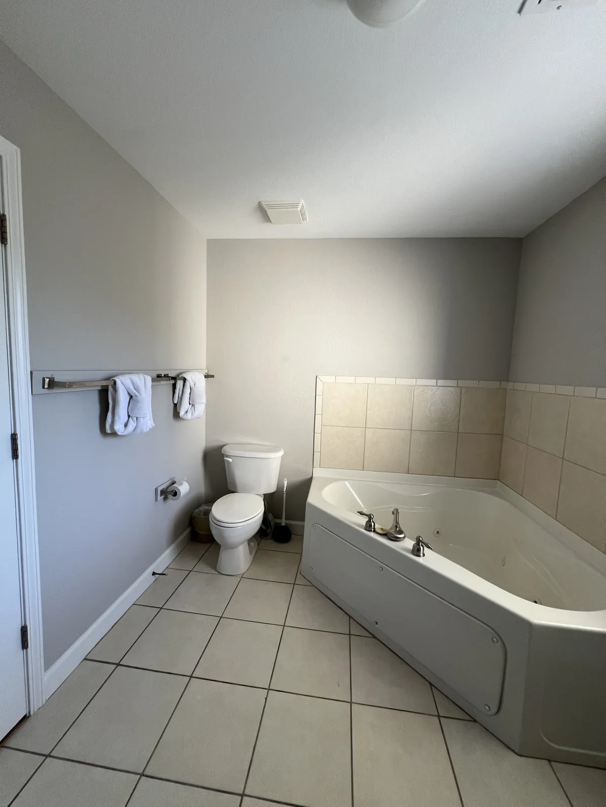 A spa-inspired bathroom featuring a whirlpool bathtub, toilet, and neatly arranged towels. The tub is the focal point, suggesting a space dedicated to relaxation and pampering after a busy day.